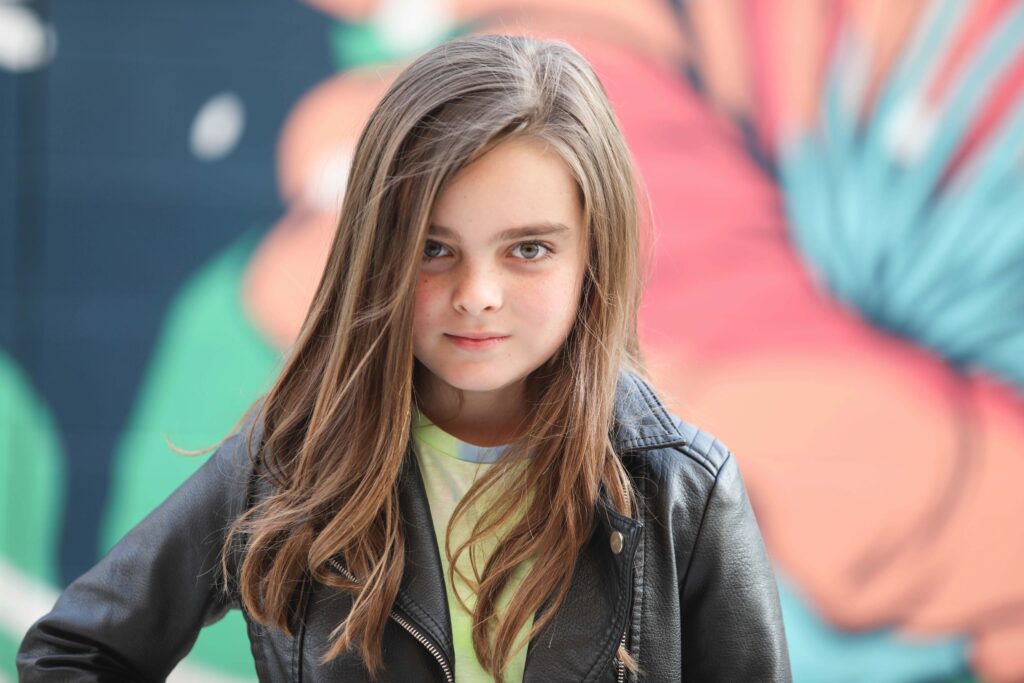 Portrait of a confident tween girl smiling during a 'Bloom Your Own Way' photo session. The image captures her radiant personality and self-assuredness, highlighting the beauty of celebrating individuality and inner strength before middle school