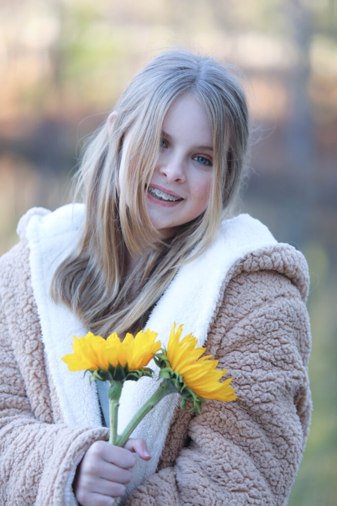 Portrait of a confident tween girl smiling during a 'Bloom Your Own Way' photo session. The image captures her radiant personality and self-assuredness, highlighting the beauty of celebrating individuality and inner strength before middle school.